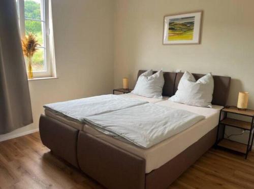 a bedroom with a bed with white sheets and pillows at Feriendomizil im Saarschleifenland in Mettlach