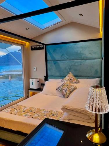 a bedroom on a boat with a bed and a window at Desert Blue Pangong By LexStays in Man