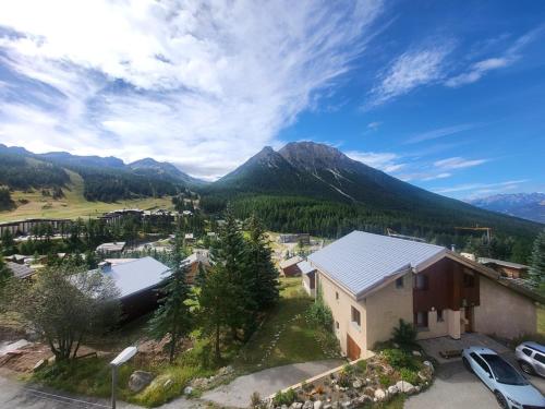 une vue aérienne d'une maison avec des montagnes en arrière-plan dans l'établissement Studio ensoleillé avec balcon au centre de Montgenèvre, proche commodités et pistes - FR-1-266-128, à Montgenèvre