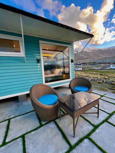 a patio with two chairs and a table and a house at Desert Blue Pangong By LexStays in Man