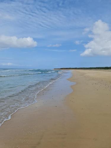 a sandy beach with the ocean and clouds in the sky at Serra's Village in Vila do Maio