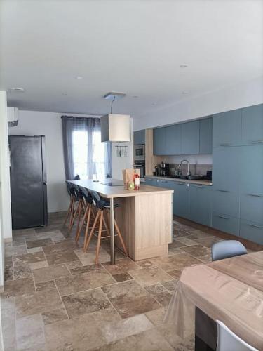 une cuisine avec des armoires bleues et une table et des chaises dans l'établissement Grande maison de vacances récente, à Saint-Denis-dʼOléron