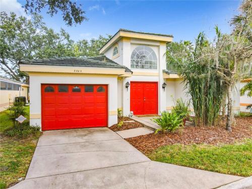 a house with red garage doors on a street at Private Pool With Heat - Close to Disney! in Kissimmee