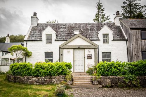 a white house with a white door at Old Kyle Farm - Stunning Views - 2 mins from Skye Bridge in Kyleakin