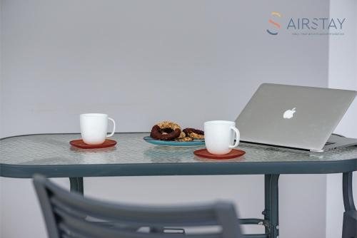 a table with a laptop and two cups and a plate of food at Zilean Apartments Airport by Airstay in Spáta