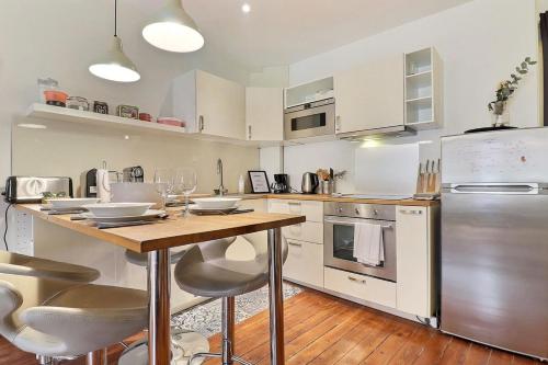 une cuisine avec une table avec des chaises et un réfrigérateur dans l'établissement Le Marius - Beautiful apartment near the Rhône - Lyon 3rd, à Lyon