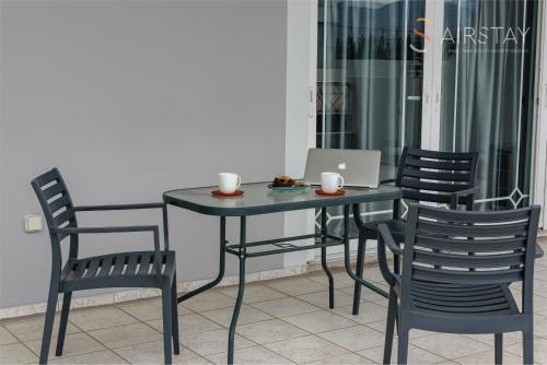 a table with chairs and a laptop computer on it at Zilean Apartments Airport by Airstay in Spáta