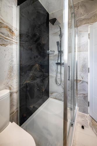 a shower with a glass door in a bathroom at Modern home with driveway parking for 2 vehicles, near Tottenham Hotspur Stadium, White Hart Lane Train Station in London