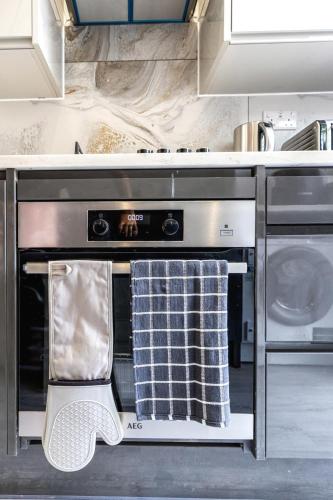 a kitchen with an oven with two towels on it at Modern home with driveway parking for 2 vehicles, near Tottenham Hotspur Stadium, White Hart Lane Train Station in London
