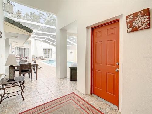 a red door in a living room with a table at Private Pool With Heat - Close to Disney! in Kissimmee