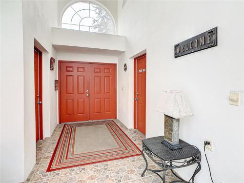 a hallway with red doors and a chair and a lamp at Private Pool With Heat - Close to Disney! in Kissimmee
