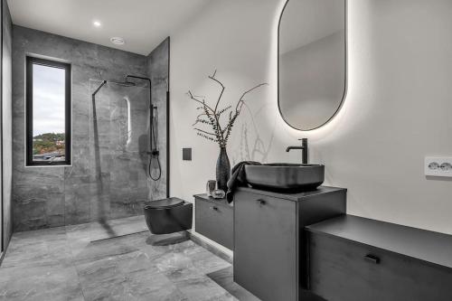 a bathroom with a sink and a shower and a mirror at Feriested ved Strand & svaberg in Kristiansand