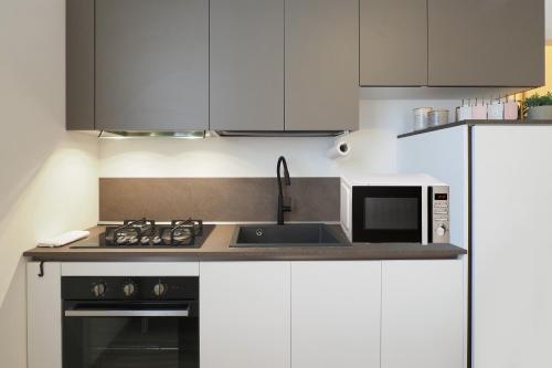 a kitchen with white cabinets and a sink and a microwave at Primopiano - Papa Giovanni in Assago