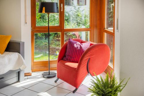 a living room with a red chair and a lamp at Viel Platz und Ruhe für 4 am Valentins-Park in Unterschleißheim