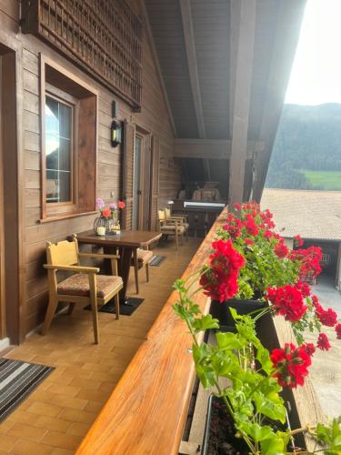 a balcony with tables and chairs and red flowers at Stroblhof in Vipiteno
