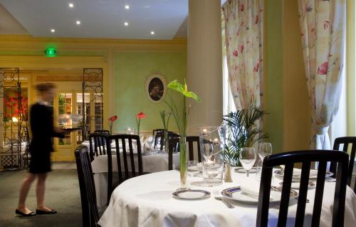 a woman standing in front of a table in a restaurant at Logis Le Midland in Vichy