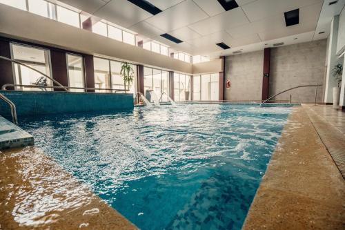 an indoor swimming pool with blue water in a building at Rayentray Grand Hotel in Puerto Madryn