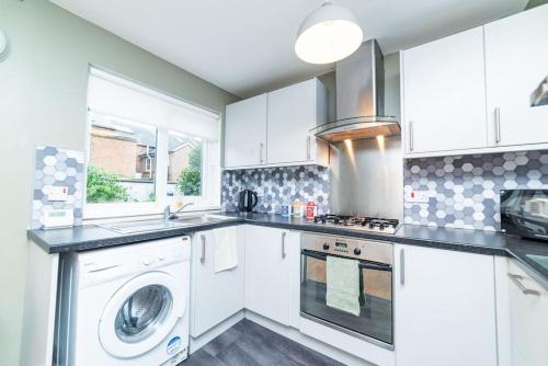 a kitchen with white cabinets and a washer and dryer at Excellent, comfortable location to visit Belfast in Holywood