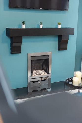 a fireplace with a tv on a blue wall at Excellent, comfortable location to visit Belfast in Holywood