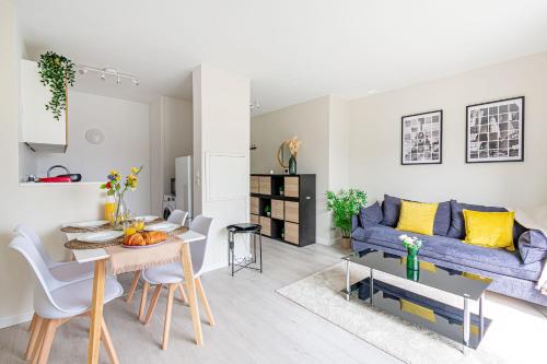 un salon avec un canapé bleu et une table dans l'établissement CosyHome - Appartement CDG Paris Nord & Parc des Expos - Parking gratuit, à Aulnay-sous-Bois