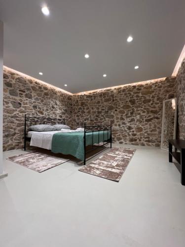 a bedroom with a bed and a stone wall at Prina Stone Retreat in Prína