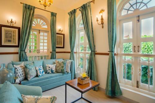 a living room with a blue couch and windows at ELIVAAS 3 BHK with Pvt Pool in Assagao -Montforte Ayada in Assagao
