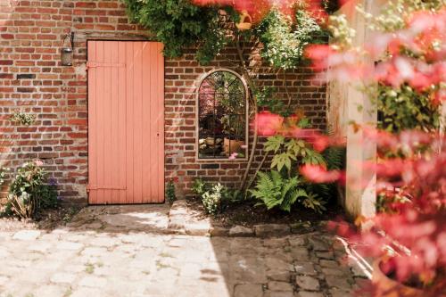 a brick building with a red door and a window at La Maison Gioia in Nerville-la-Forêt