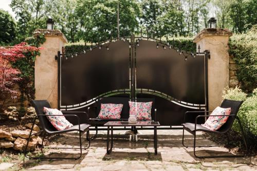 a black gate with two chairs and a table with pillows at La Maison Gioia in Nerville-la-Forêt