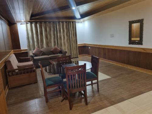 a living room with a table and a couch at Vivaan The Sunrise in Manāli