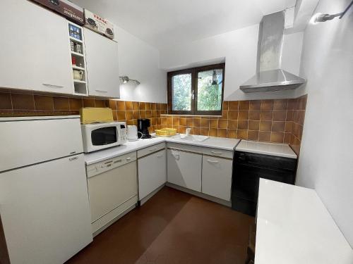 une petite cuisine avec des armoires blanches et un micro-ondes dans l'établissement Alpee 1 - Appartement proche pistes de ski, à La Clusaz