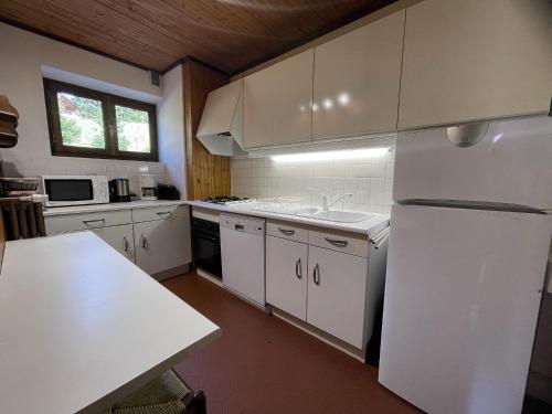 une cuisine avec des armoires blanches et un réfrigérateur blanc dans l'établissement Alpee 3 - Appartement proche pistes de ski, à La Clusaz