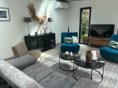 un salon avec un canapé, des chaises et une télévision dans l'établissement Maison spacieuse, à Saint Lo