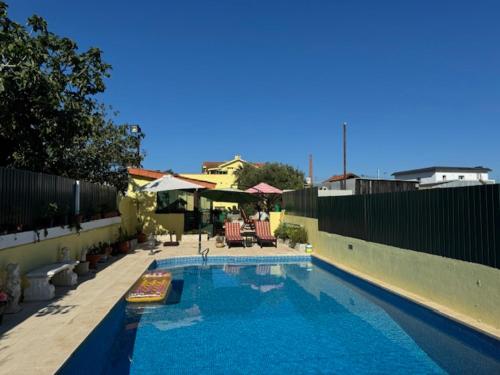 a swimming pool with two chairs and a fence at 200M - Train Station Barrinha Beach House & Pool in Esmoriz