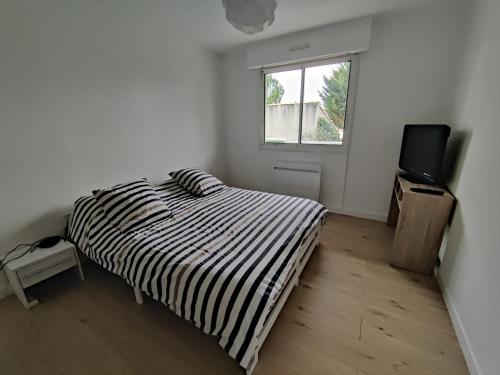 une chambre blanche avec un lit et une télévision dans l'établissement Royan Condo 2bedrooms WiFi Parking, à Royan