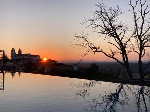 a pool with the sunset in the background at Casa do Vidoeiro in Seia