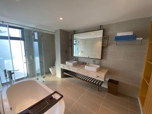 a bathroom with a tub and a sink and a mirror at Phoenix Pool & Golf View Villa Cam Ranh in Cam Ranh