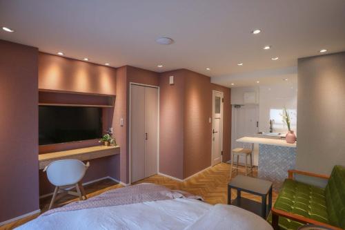 a bedroom with a bed and a television and a kitchen at Shinjuku Waseda Hostel in Tokyo