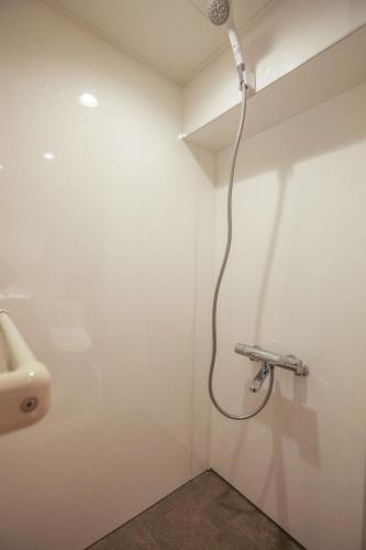 a shower in a bathroom with a sink at Shinjuku Waseda Hostel in Tokyo