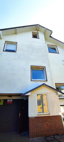 a tall white building with windows and a garage at Adam room piwnica in Wrocław