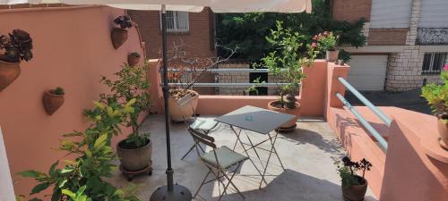 - un balcon avec une table, des plantes en pot et un parasol dans l'établissement CHAMBRE SPACIEUSE DANS MAISON ART DECO au CENTRE DE TOULOUSE, à Toulouse