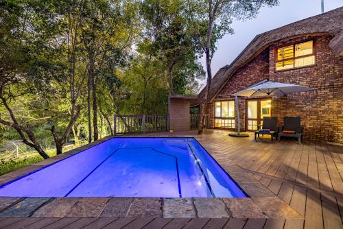 an image of a swimming pool in front of a house at Kruger Park Lodge - IKZ2 - 3 Bedroom Chalet in Hazyview