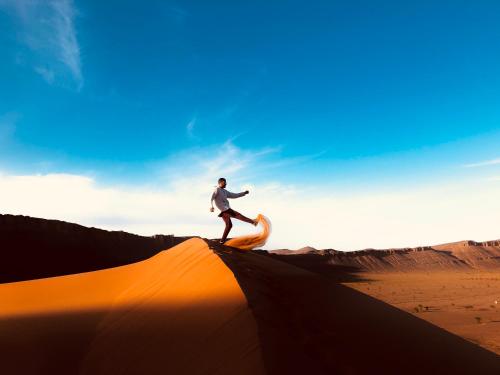 a man standing on top of a dune in the desert at Auberge Hassi Fougani in Tafraoute Sidi Ali