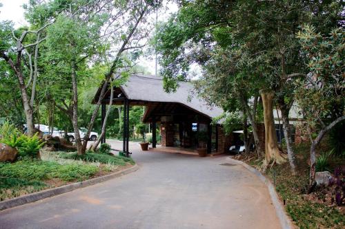 a building with a walkway in a park with trees at Kruger Park Lodge - IKZ2 - 3 Bedroom Chalet in Hazyview