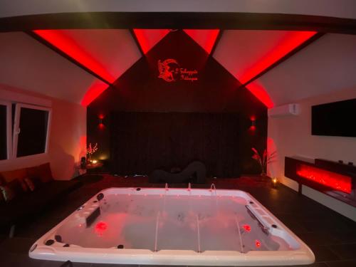 a large bath tub in a room with red lights at Gîte et Spa L' Echappee Feerique in Fresnicourt-le-Dolmen