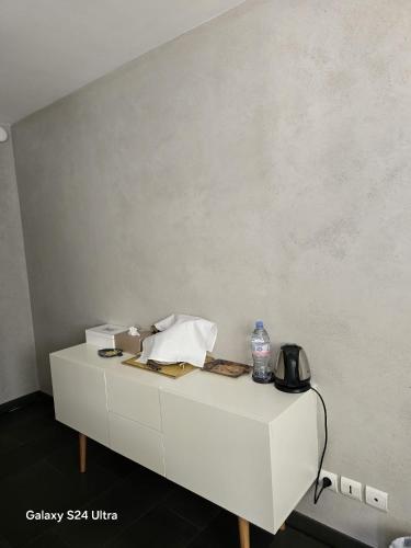- une table blanche avec un téléphone et une bouteille d'eau dans l'établissement chambre privative au rez de jardin dans villa, à La Wantzenau