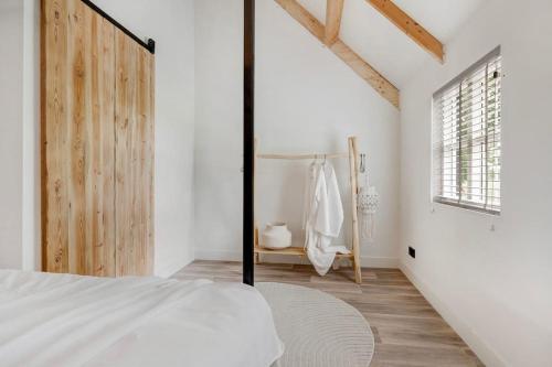 a bedroom with a white bed and a window at Luxe vakantiehuis in dijkboerderij in Zuid-Beijerland