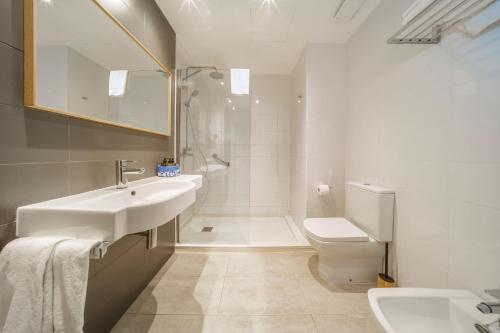 a white bathroom with a sink and a toilet at Mar Calma Hotel in Port de Pollensa