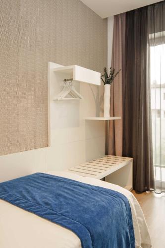 a white bedroom with a bed with a blue blanket at Mar Calma Hotel in Port de Pollensa