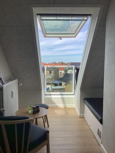 a living room with a large window and a table at Lækker ny lejlighed med eget Badeværelse in Hirtshals