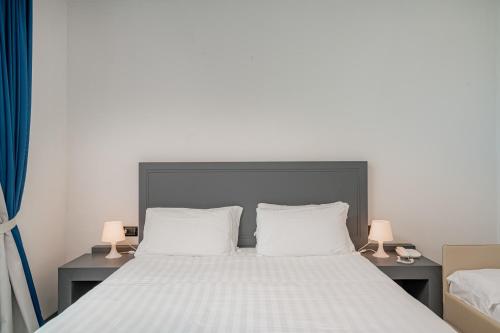 a bed with two white pillows and two lamps at Bellevue Sardinia Resort Affiliated by Meliá in Valledoria